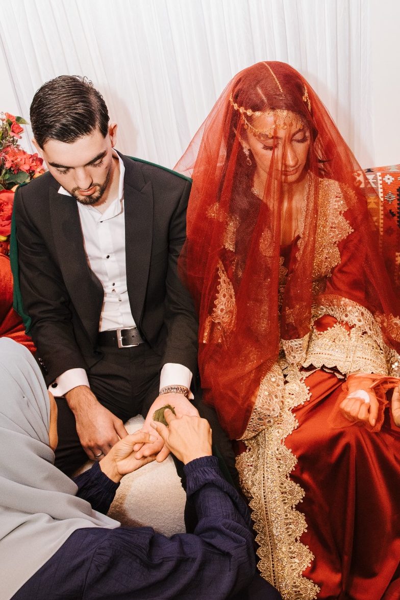 Henna Ceremonie Visuals by Nicoline Een bruid met een rode sluier en een bruidegom tijdens een traditionele ceremonie.